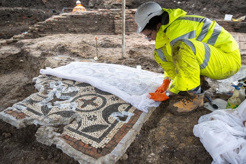 An archaeologist laying a piece of netting over a small mosaic
