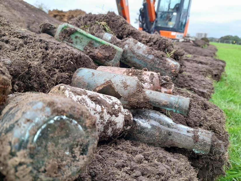 Photo of muddy glass bottles found during excavation.