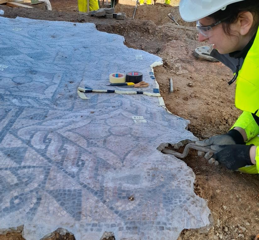 Conservation team member using tools to remove the mosaic from the mortar