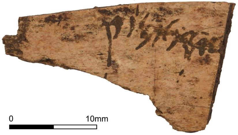 A flat piece of bone with a word carved into it