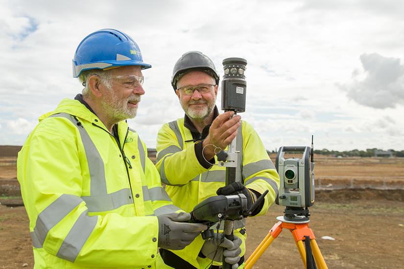 Supervisor Tom shows a volunteer how to use the surveying equipment