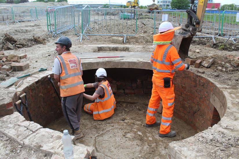 Photo of three archaeologists inside the circular gun emplacement excavating it