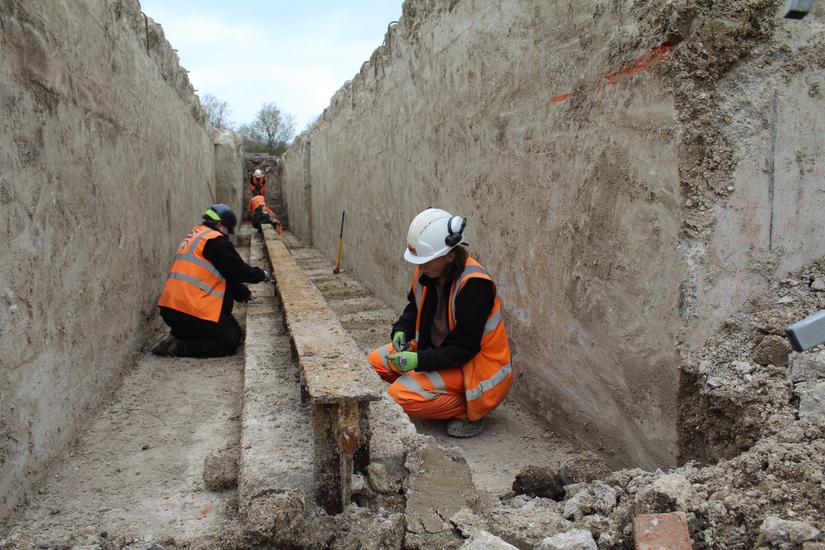 Photo of archaeologists excavating the metal rail in one of the catapult arms