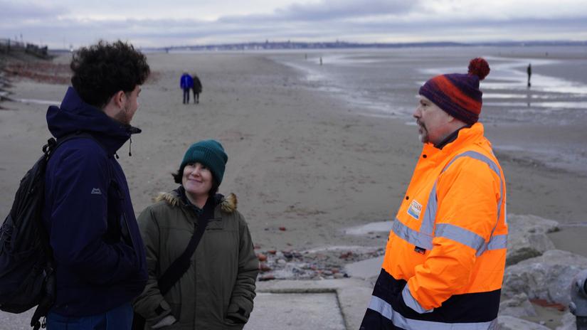 Three people talking on a beach