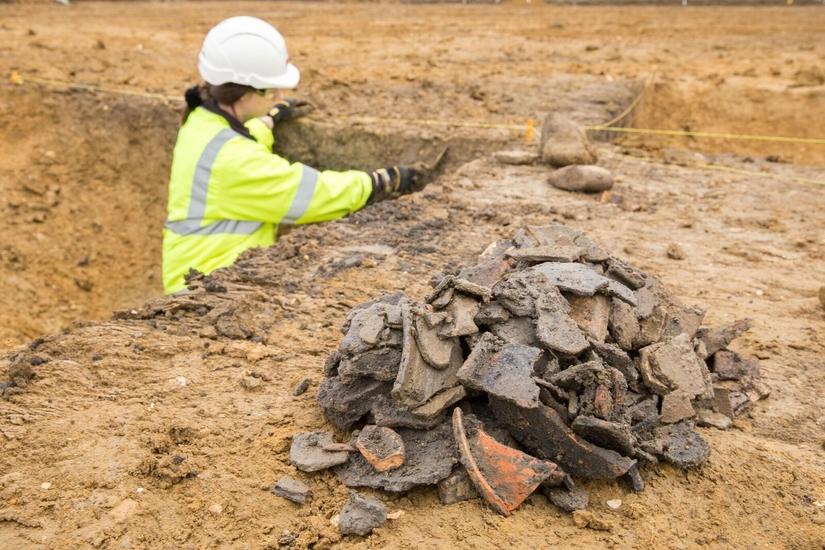An archaeologist excavating next to a big pile of pottery