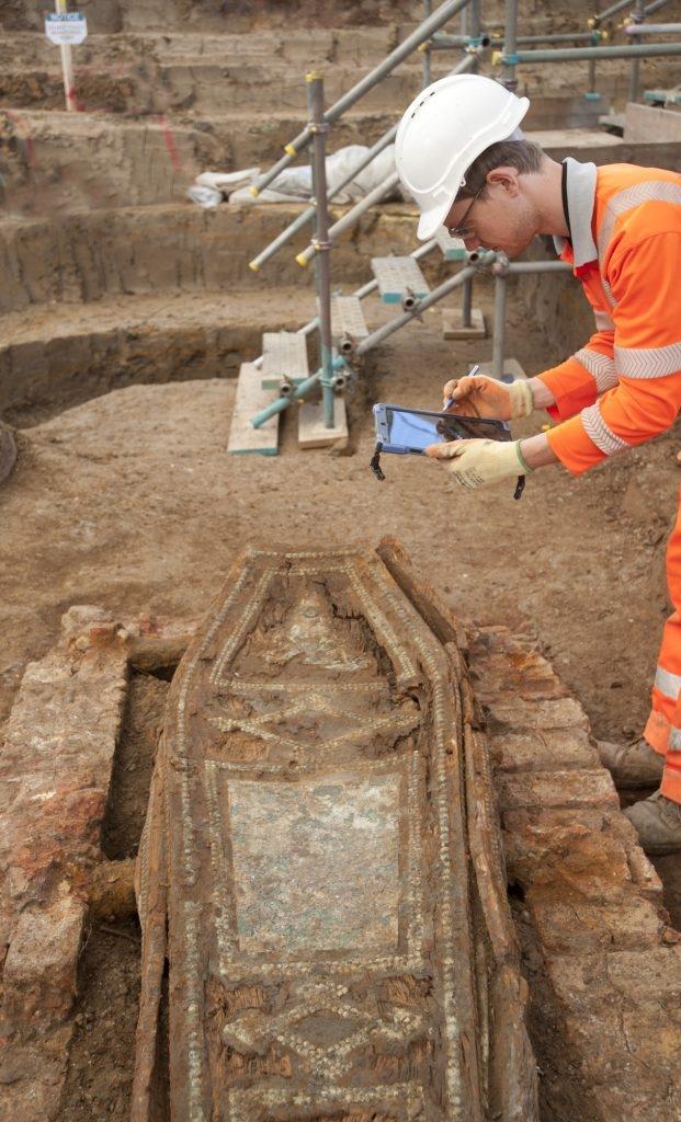 Archaeologist recording a coffin with a tablet