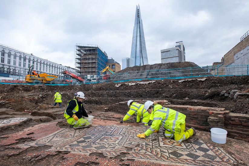 A group of archaeologists excavating a mosaic with the london skyline in the background