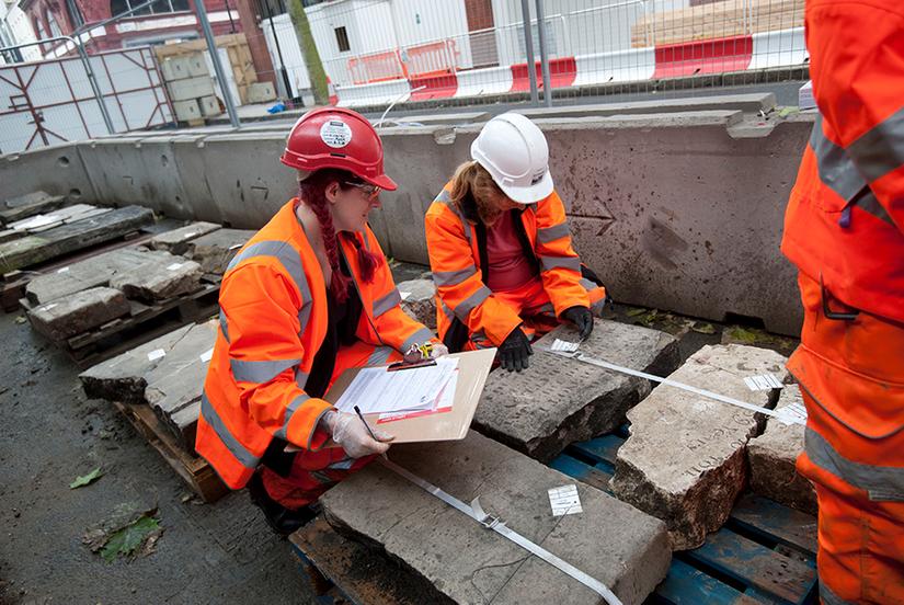 Two people recording the inscription on a gravestone