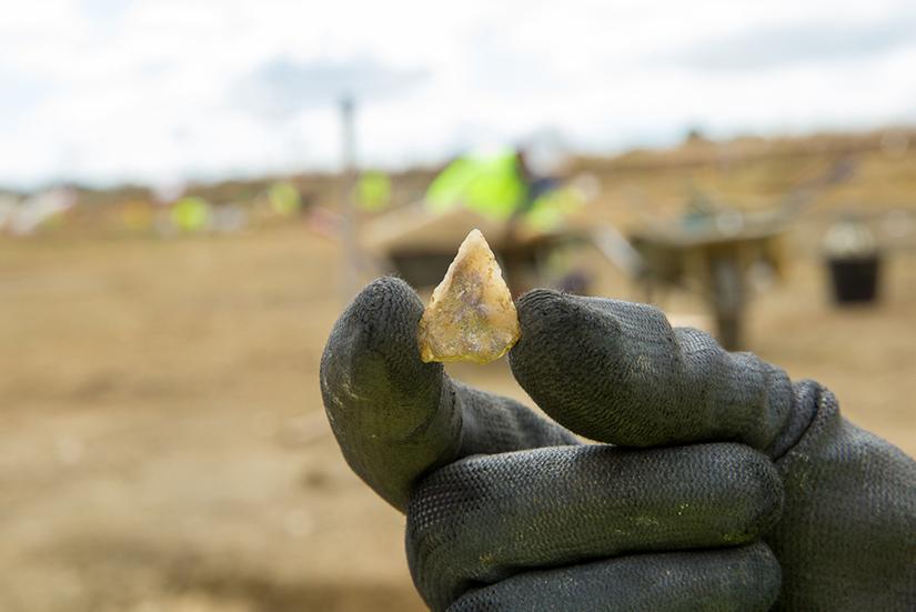 A gloved hand holding a small arrowhead