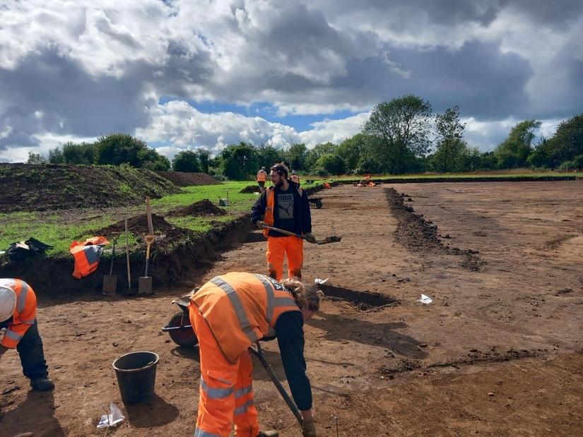 Three archaeologists excavating in a field