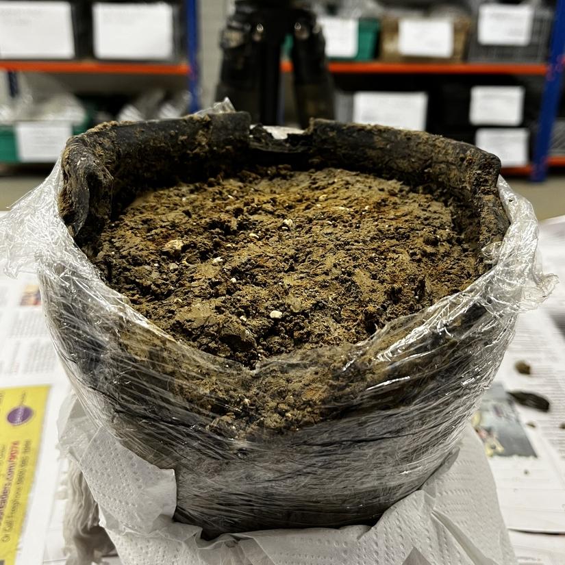 A pot filled with soil and wrapped in plastic