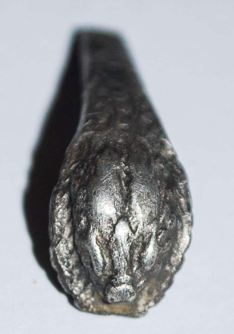 The end of a silver bracelet which is decorated with a snake-like face
