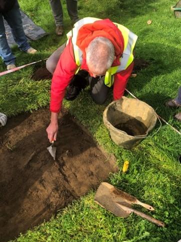 Volunteer using a trowel to excavate the test pit