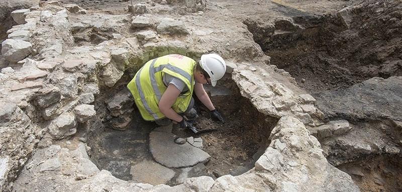 An archaeologist excavating a small circular stone structure