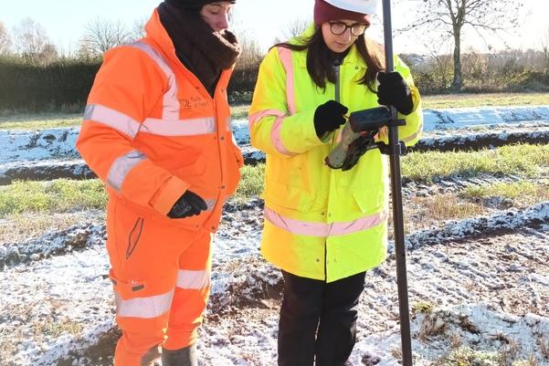 Two archaeologists using survey equipment to record the site