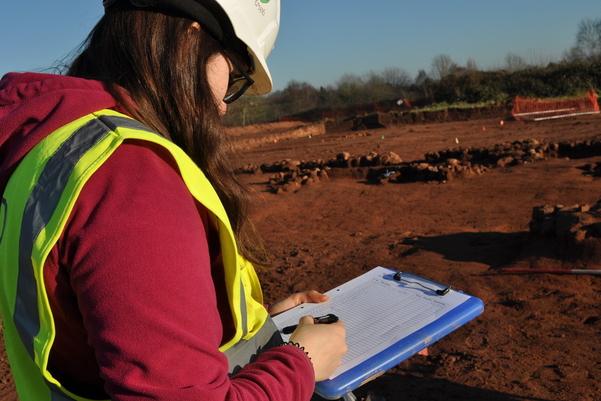 Archaeologist with a clip board filling out the paper photo register