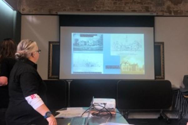 A presenter standing in front of a powerpoint presentation