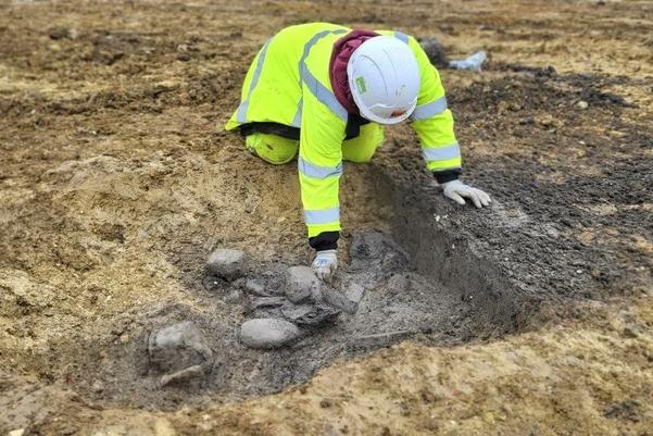 archaeologist excavating pottery and animal bone from a ditch