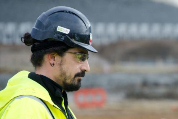 The shoulders and head of a man wearing high vis PPE and a black hard hat