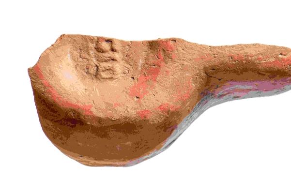 Half of an oil lamp, the remains are in the shape of a lower case letter b, with a round bowl and a long handle. it has the remains of a stamp on the bottom with the letters IEGIDI
