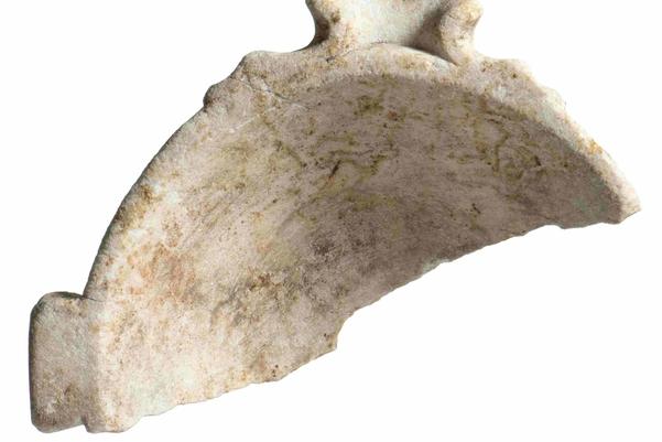 A semi-circular fragment of a white marble bowl. It has a large spout on one side and a handle on another.