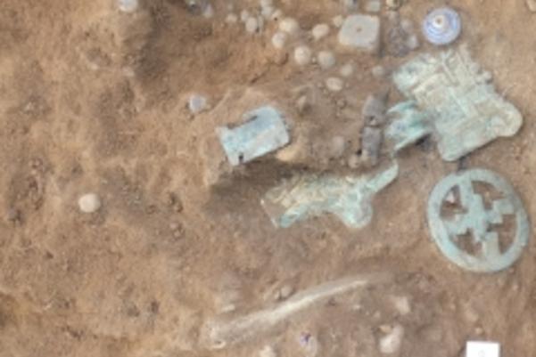 Photo of brooch and other metal items as they were found in the ground by archaeologists