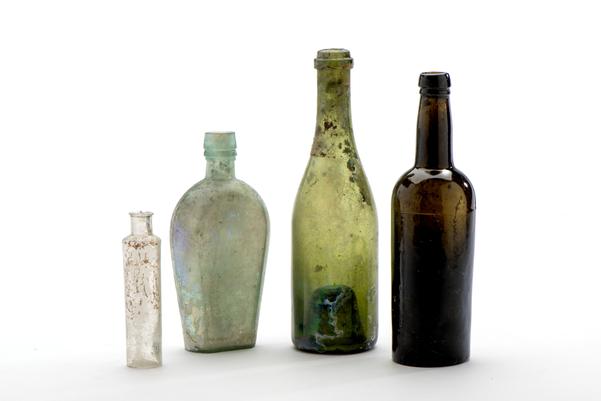 Four glass bottles, two green, one brown and one clear