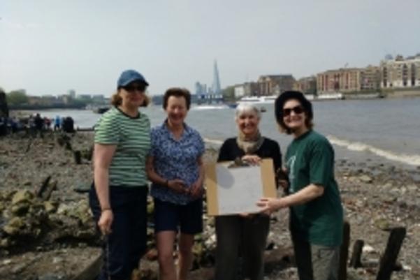 Photo of volunteers showing their drawn plan of an archaeological feature