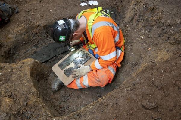 An archaeologist examines a coffin plate at St James’s burial ground
