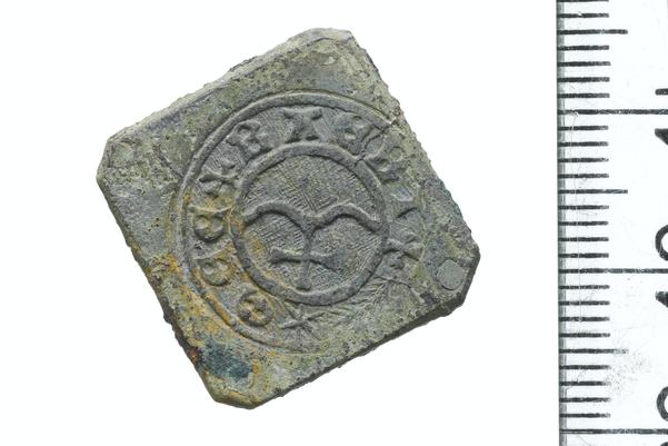 A small metal token with an emblem stamped in the centre