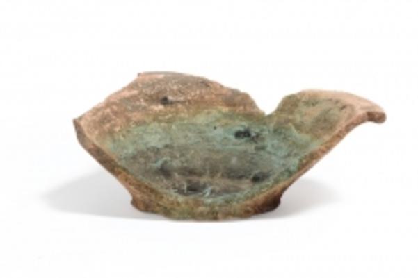 Photo of remains of a dish with copper residue, showing the base and half of the side intact