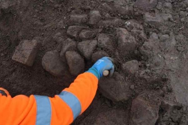 An archaeologists excavating a rubble wall