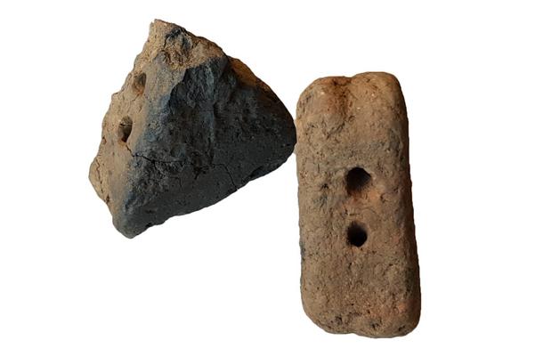 Two clay loomweights, both triangular in shape