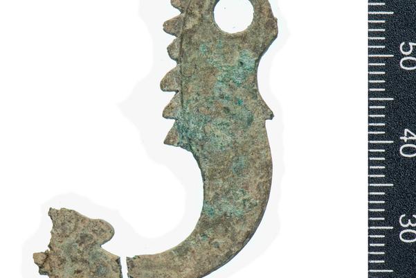 A piece of metal armour fitting shaped like a dolphin