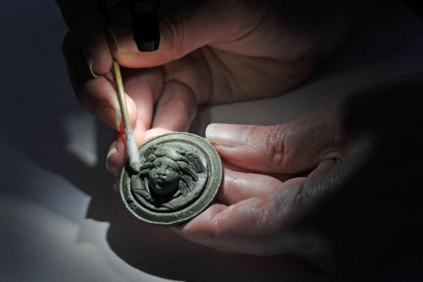 Photo of an archaeologists cleaning the mount with a cotton bud