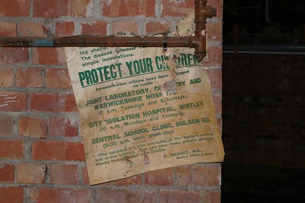 The remains of a poster on a brick wall. The poster text reads "protect your children"