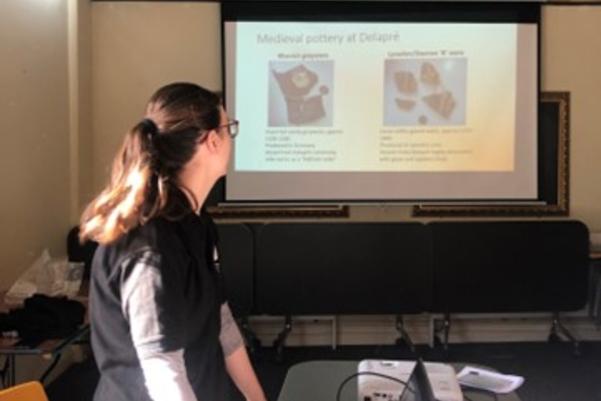 A presenter standing in front of a powerpoint presentation