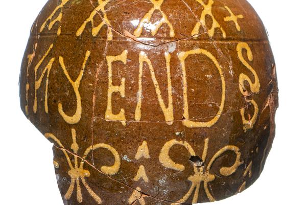 Broken piece of brown jug with yellow decorations and the words 'thy end'
