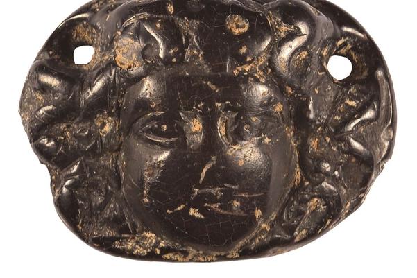 A oval pendant with a face surrounded by snake-hair