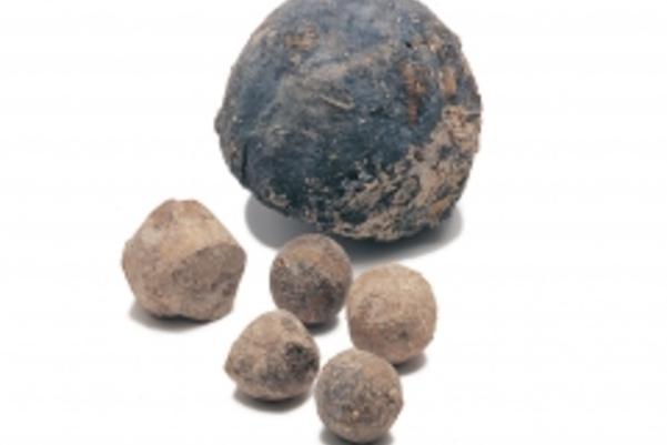 Photo of a cannonball and five smaller musket balls