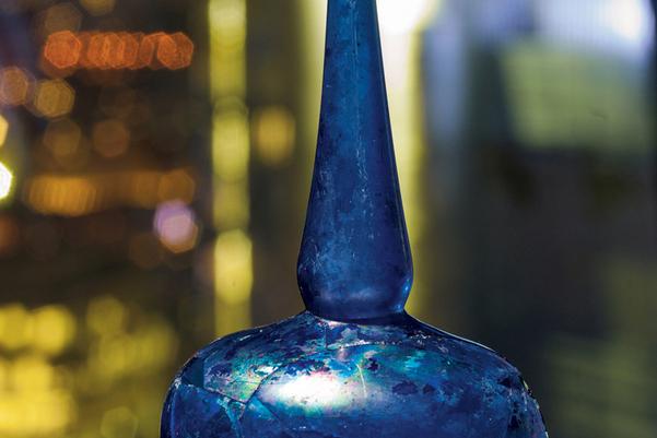 The reconstructed sprinkler. It is a dark blue glass bottle which is round at the bottom with a long pointed top