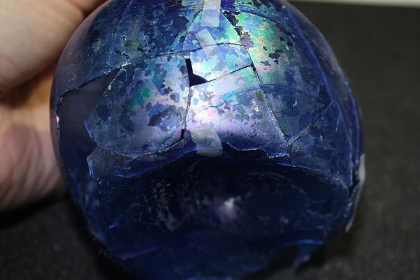 Side of the glass bottle held together with small pieces of tape