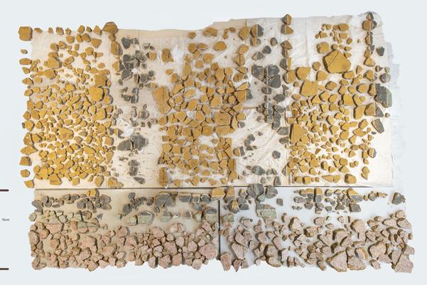 The yellow and pink panels laid out on a white background. they are very fragmented but a lot of the pieces are there